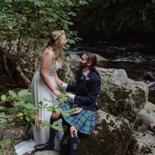 elopement couple by waterfall on wedding day in wedding dress and kilt laughing