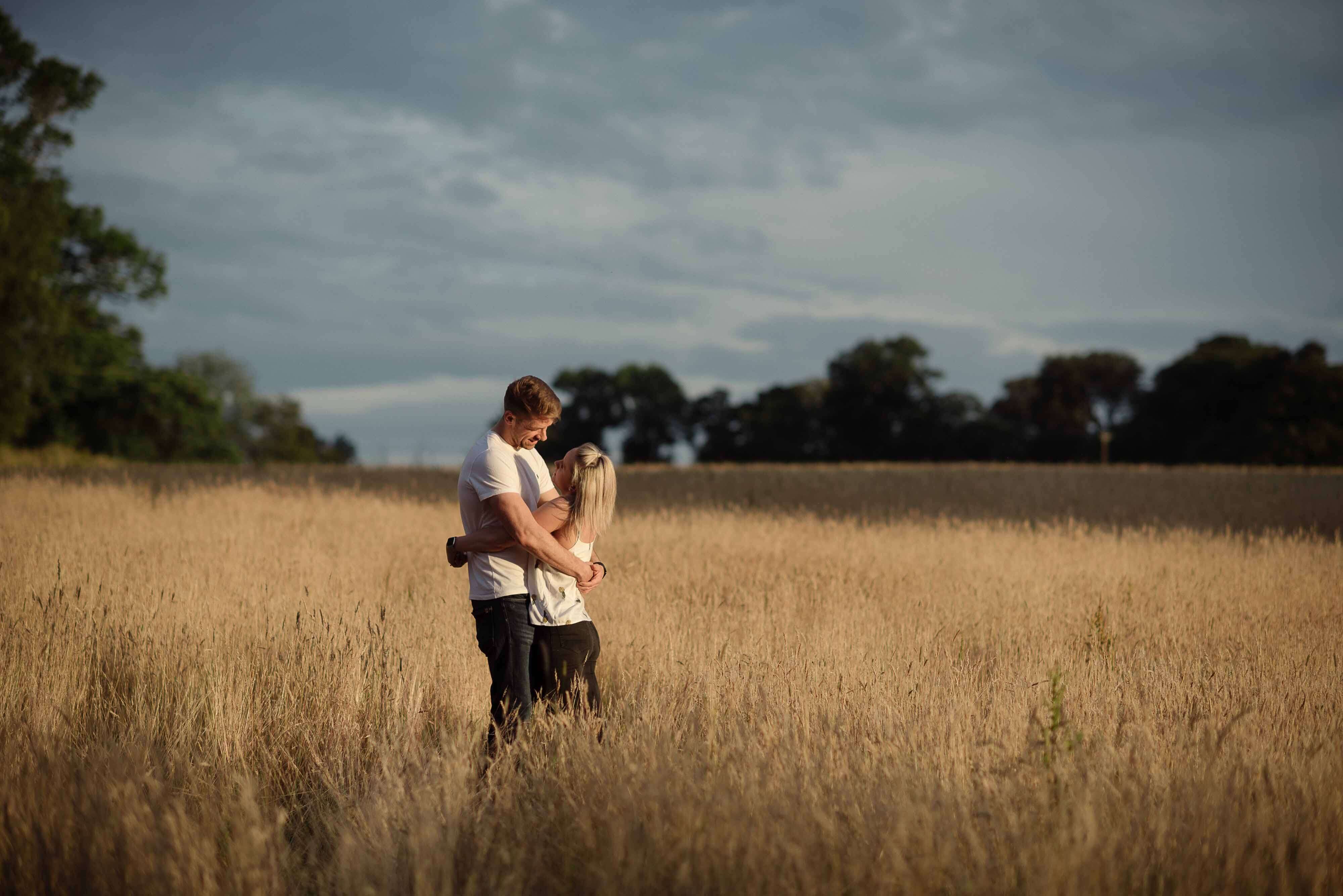 Adventure Session Photography engagement photo of couple in hay field in sun scotland