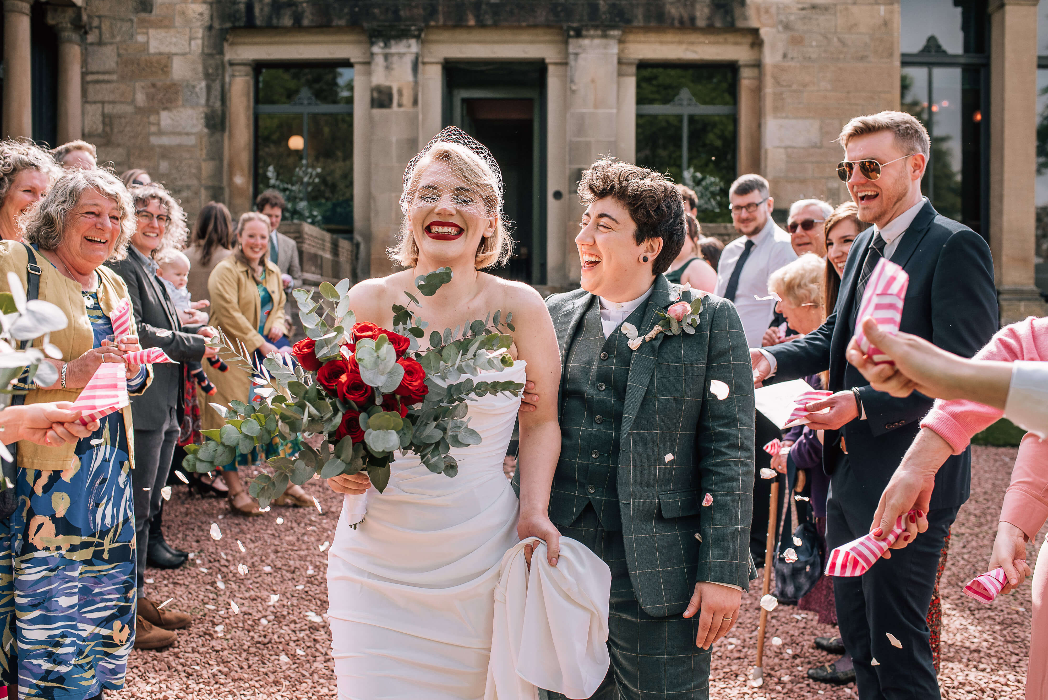 Alternative Wedding Photographer Scotland couple walking through confetti and smiling