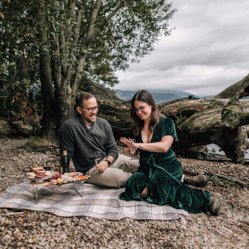 woman gazes at her engagement ring on the banks of loch lomond captured by surprise proposal photographer scotland