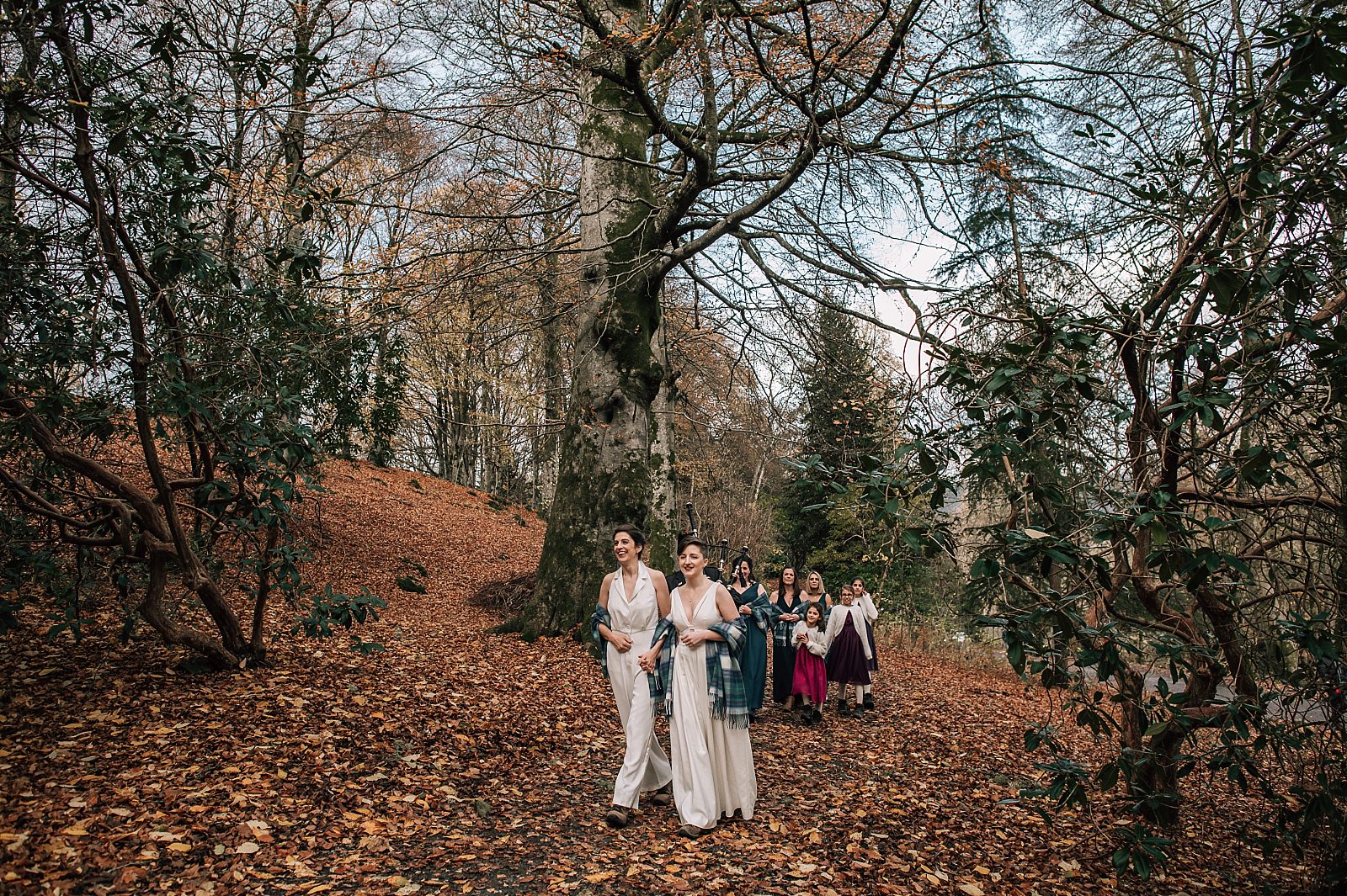 two brides walking through the woods with their wedding party at their boreland loch tay wedding day with outdoor ceremony