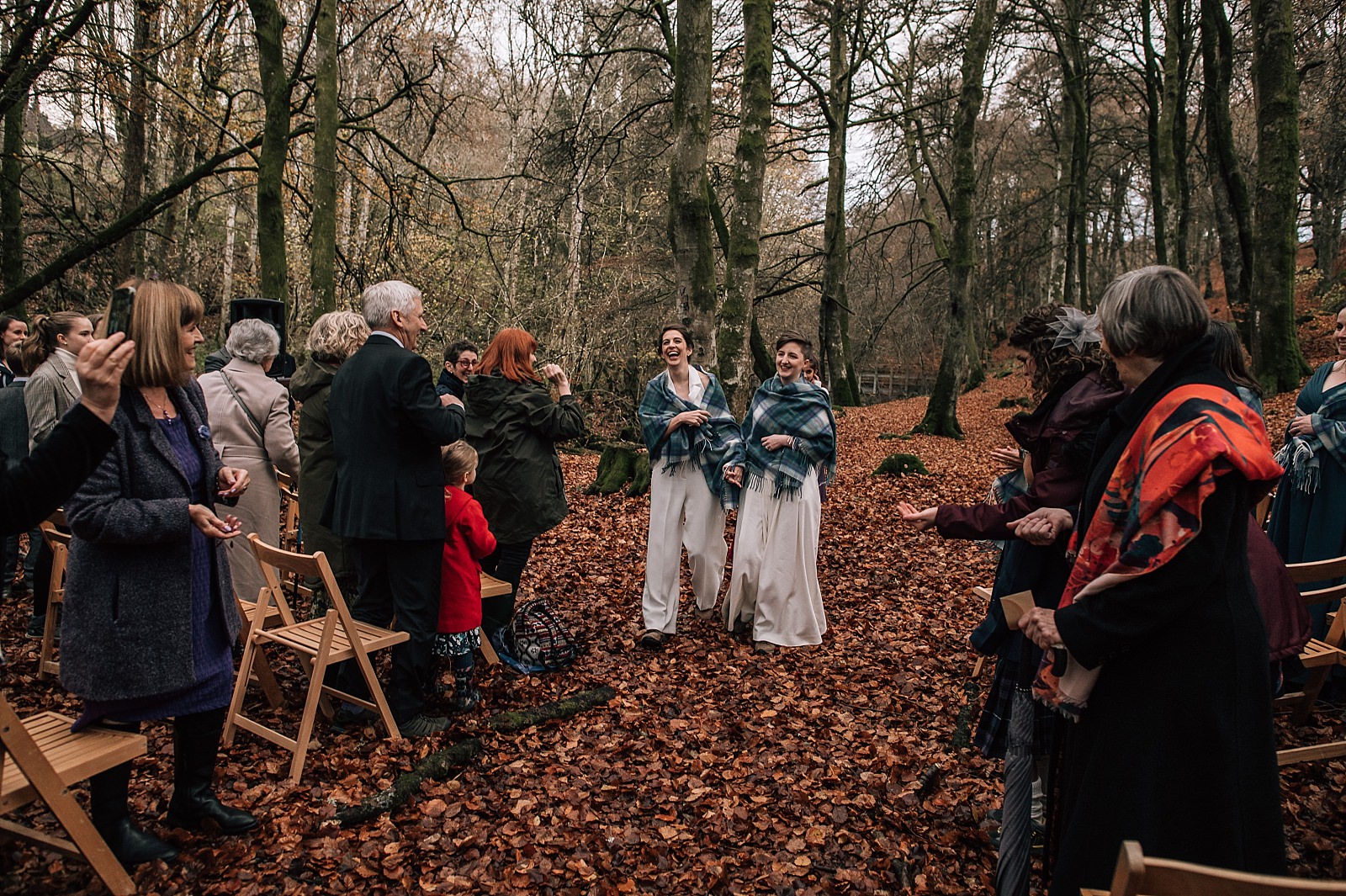two brides walking through the woods up the aisle at their boreland loch tay wedding day with outdoor ceremony
