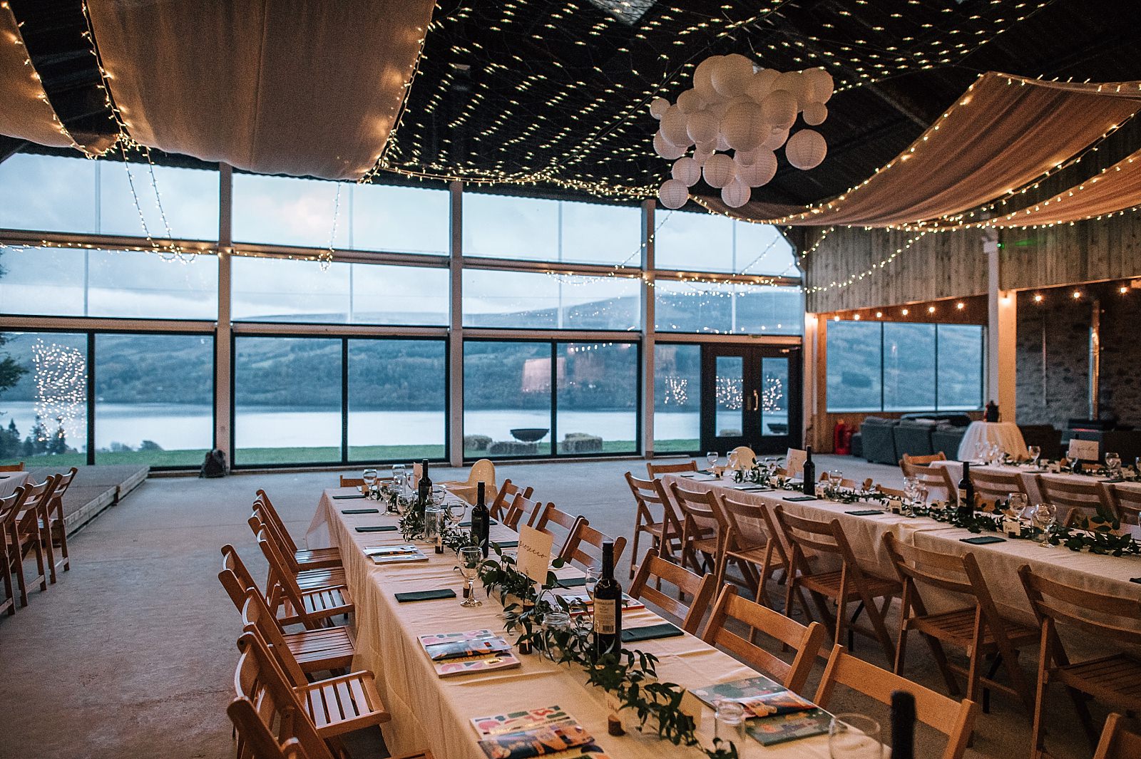interior of boreland loch tay wedding venue set up for reception dinner wedding event with wooden tables and chairs and fairy lights