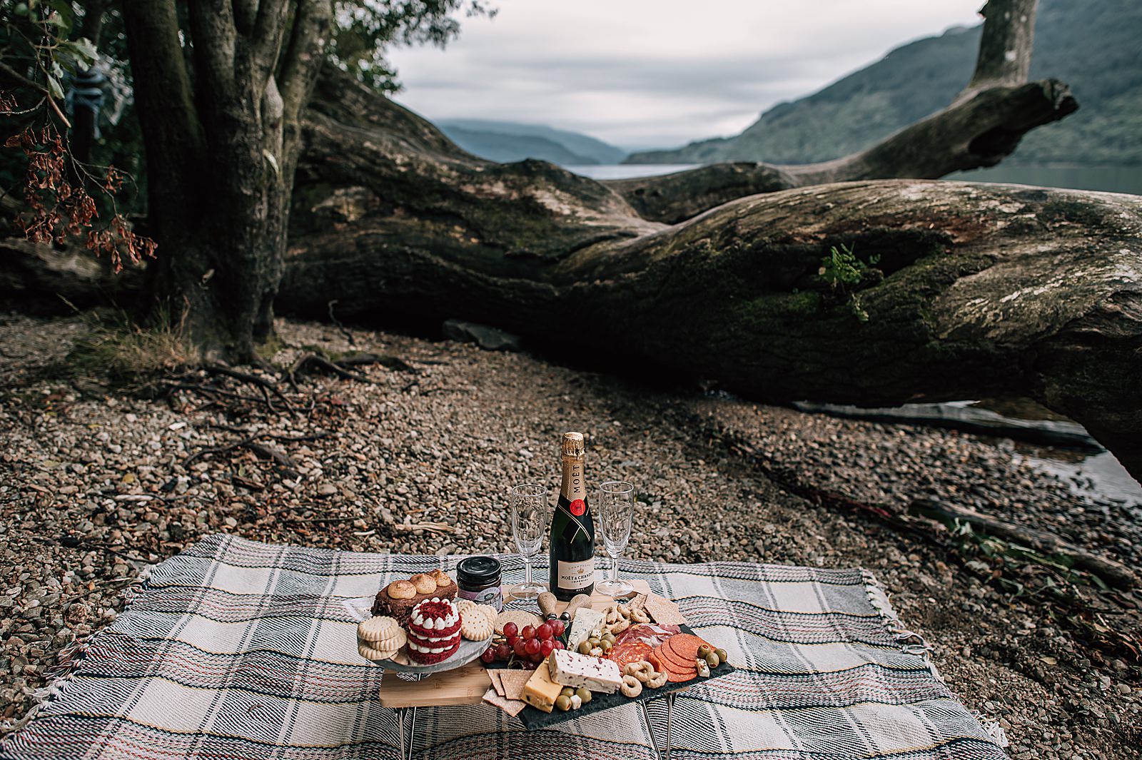 luxury picnic with champagne on picnic blanket on shore of Loch Lomond shot by proposal photographer scotland
