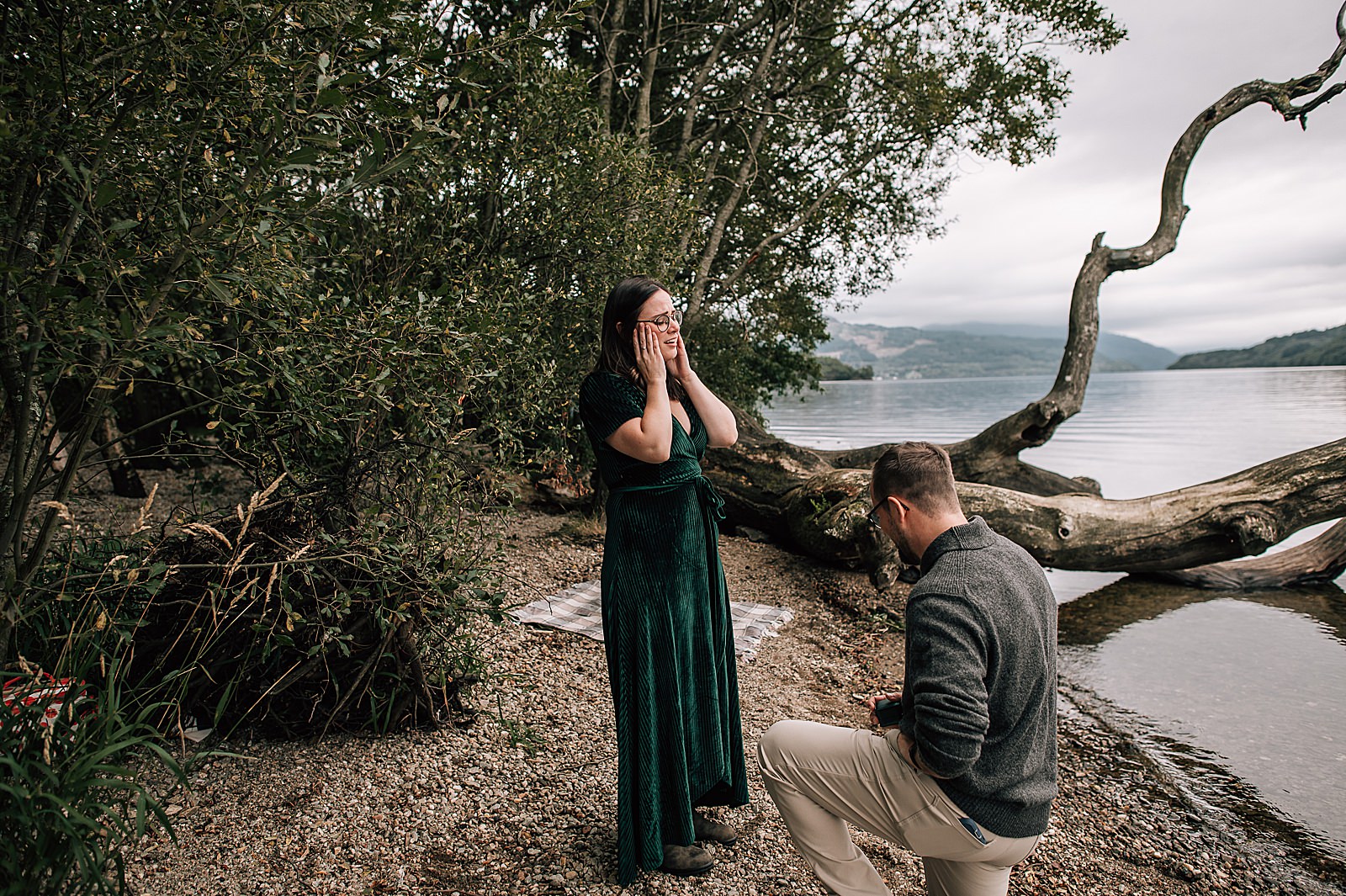 couple standing on shores of Loch Lomond during surprise proposal scotland shot by proposal photographer scotland