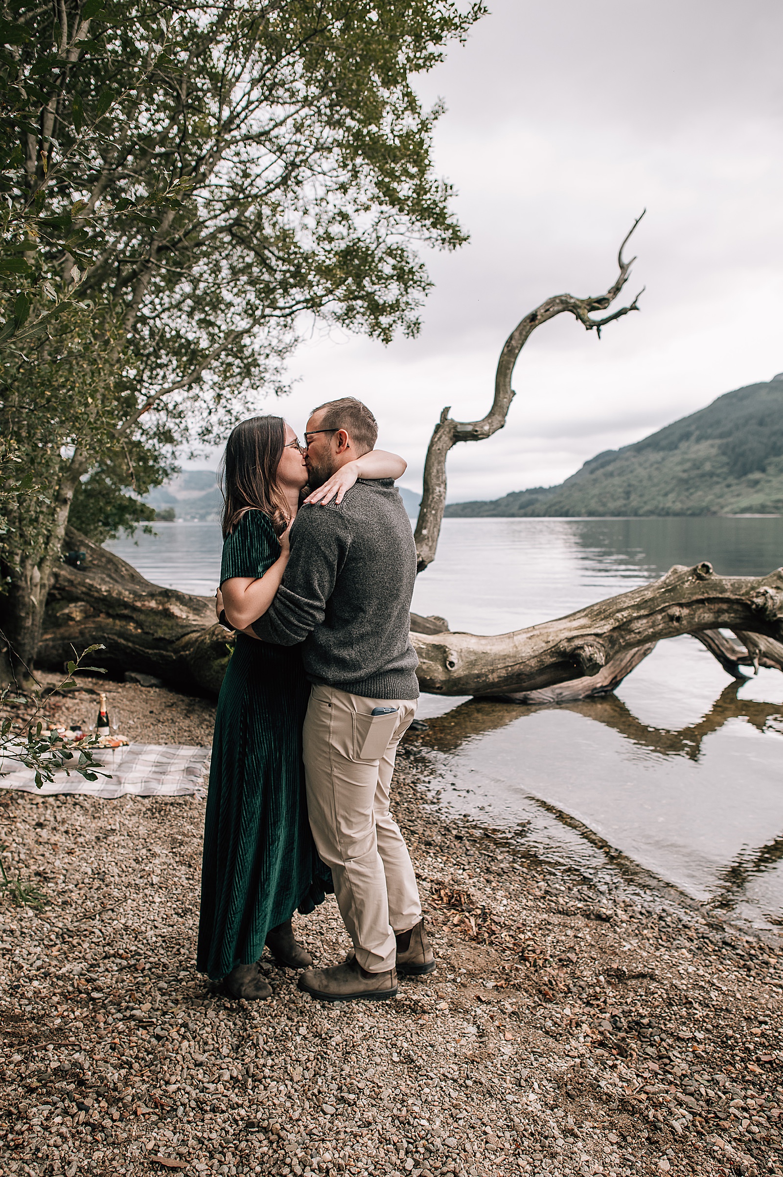 couple kissing on beach at Loch Lomond after surprise proposal scotland with photos taken by engagement photographer scotland