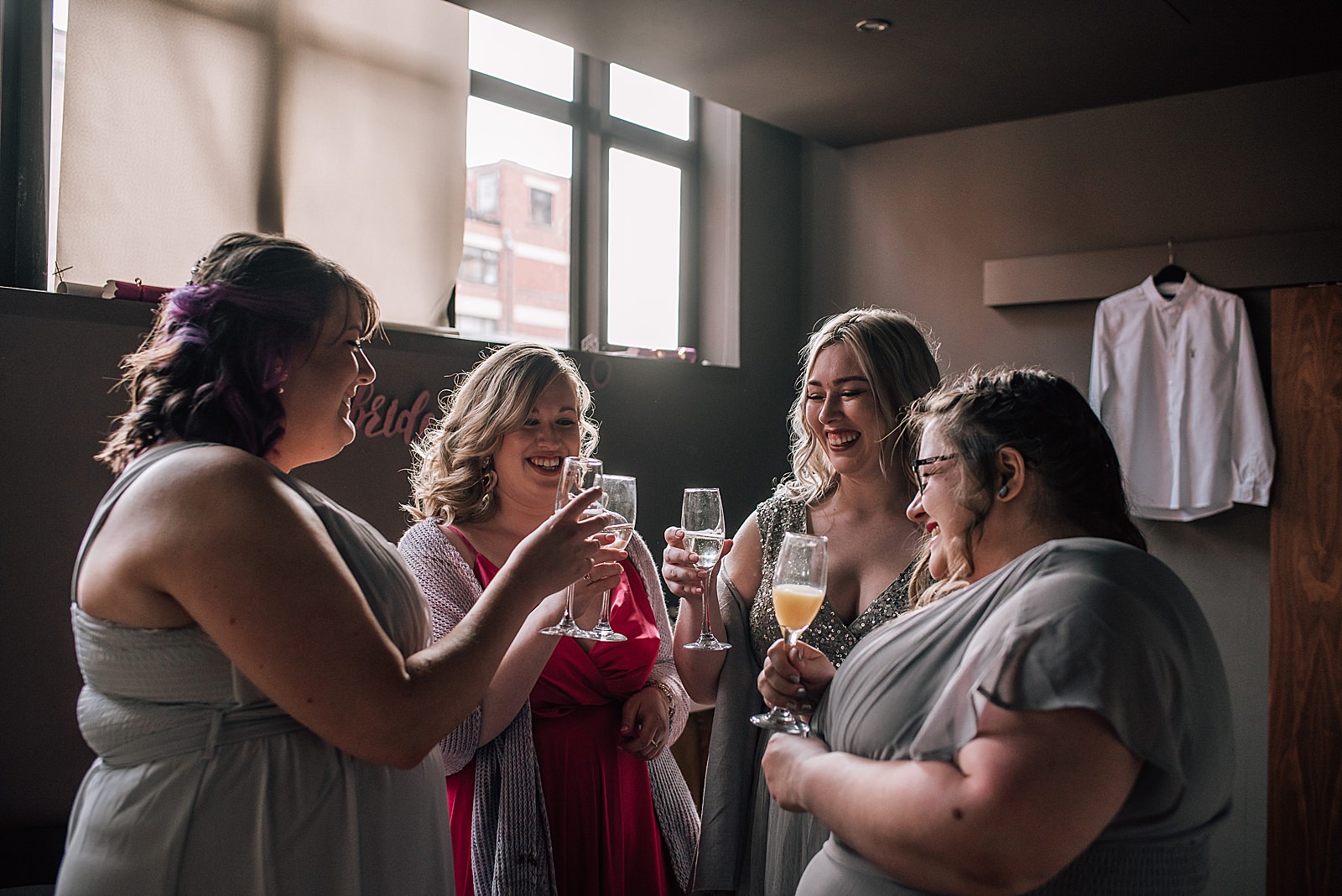 bride and bridesmaids cheers with champagne before wedding ceremony at west on the green brewery Glasgow Scotland