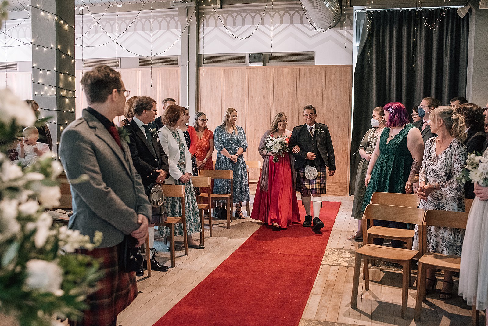 bride in pink wedding dress walks down the aisle with her father at west brewery wedding shot by alternative wedding photographer glasgow