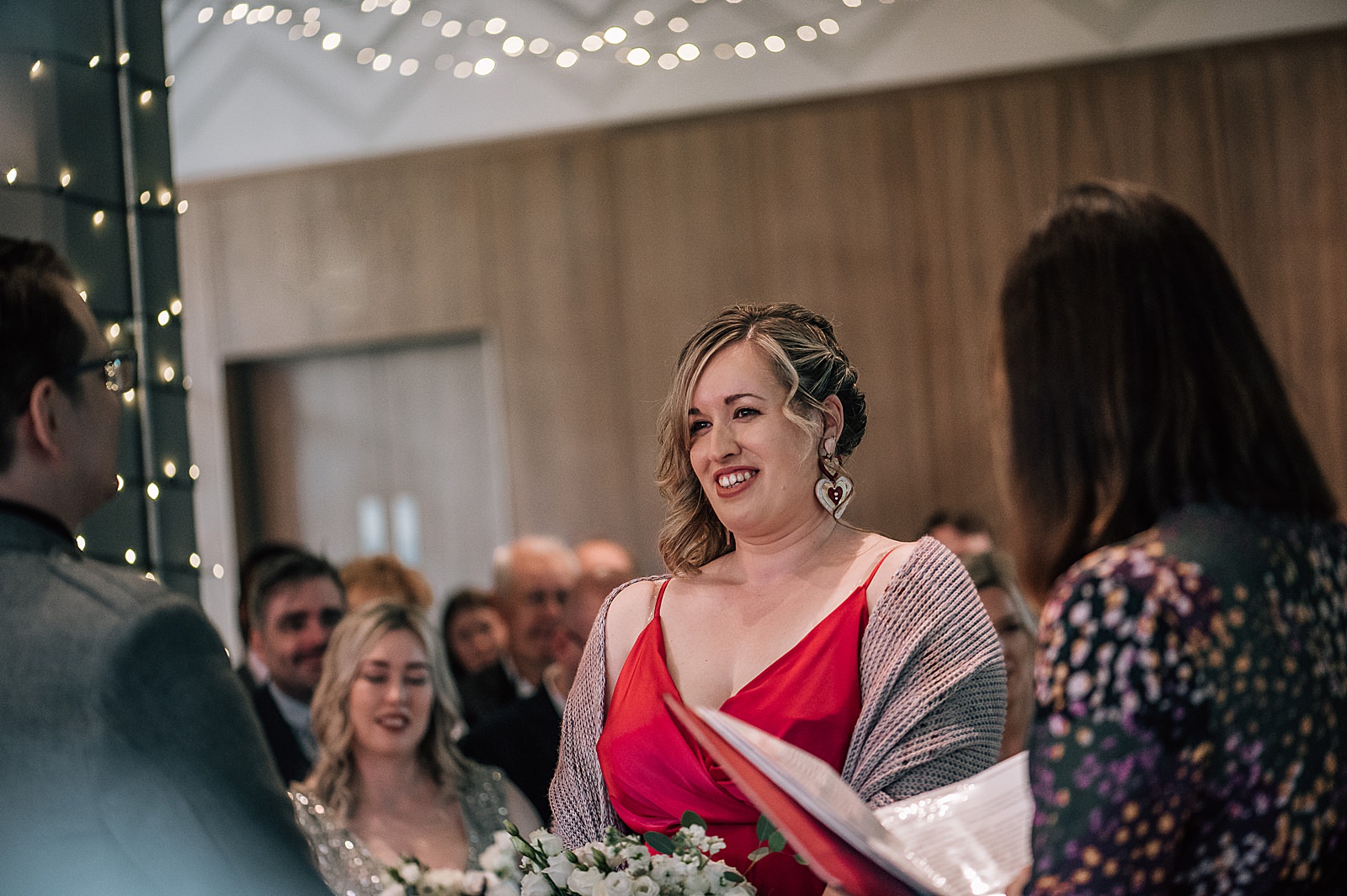 bride dressed in satin pink wedding dress with pink shawl and love heart earrings during her unique wedding at west on the green Glasgow Scotland
