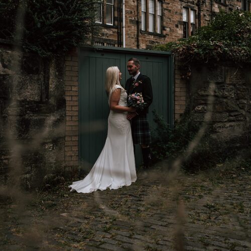 bride and groom standing in cable stoned alleyway after their the bothy glasgow wedding
