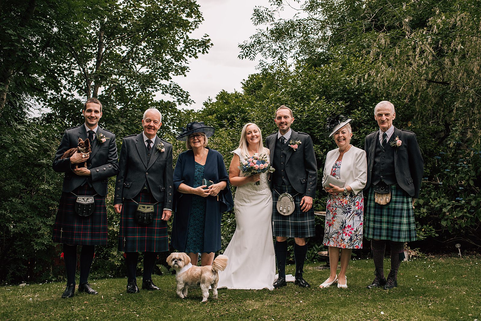 happy family wedding portrait in garden before the bothy glasgow wedding with a little dog in bowtie