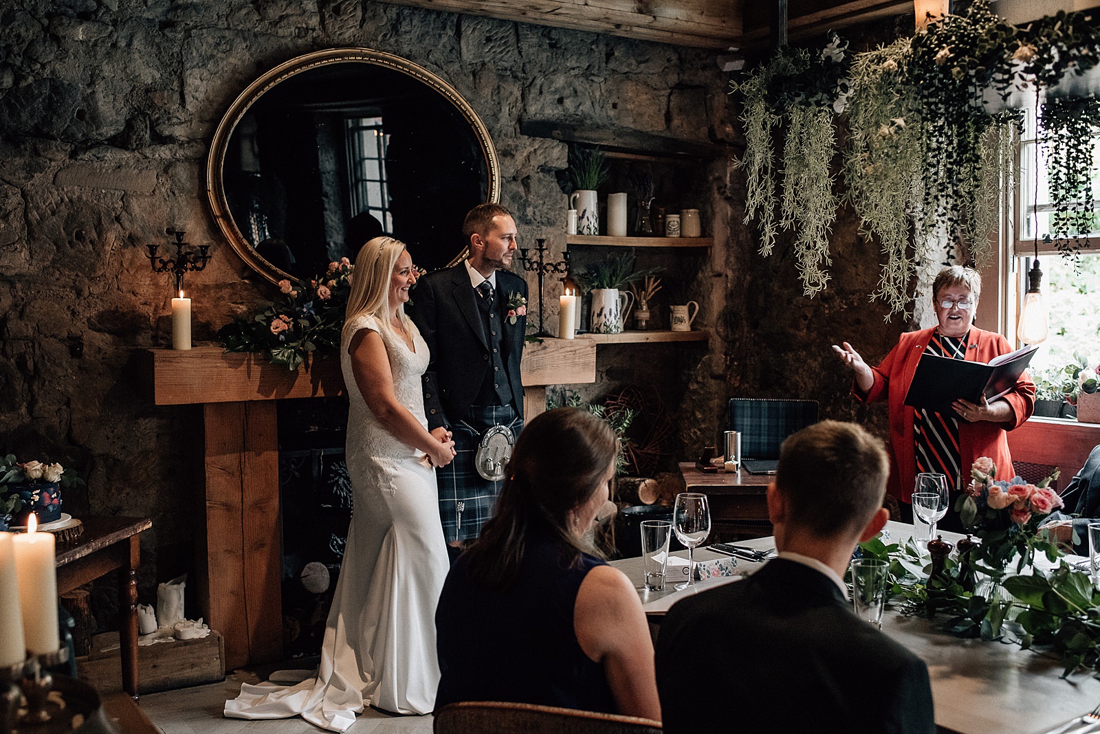 bride and groom smiling and standing in front of fireplace in the scullery at the bothy glasgow during their west end wedding glasgow
