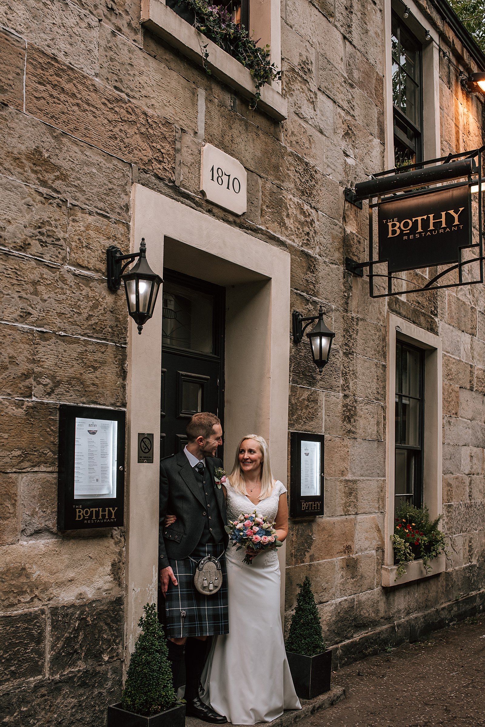 bride and groom smiling standing in doorway of the bothy glasgow during their wedding at this west end wedding venue