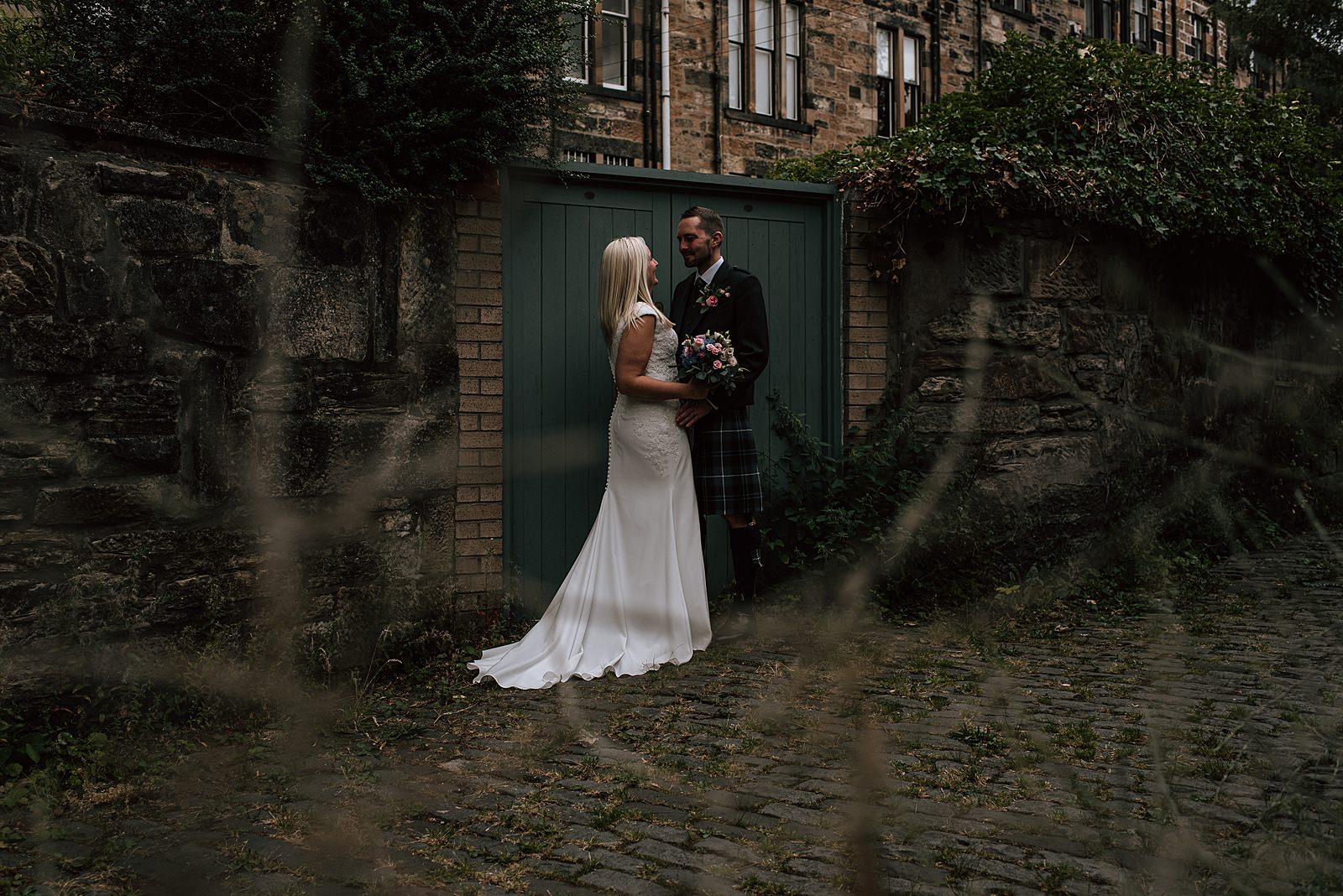 bride and groom standing in cable stoned alleyway after their the bothy glasgow wedding