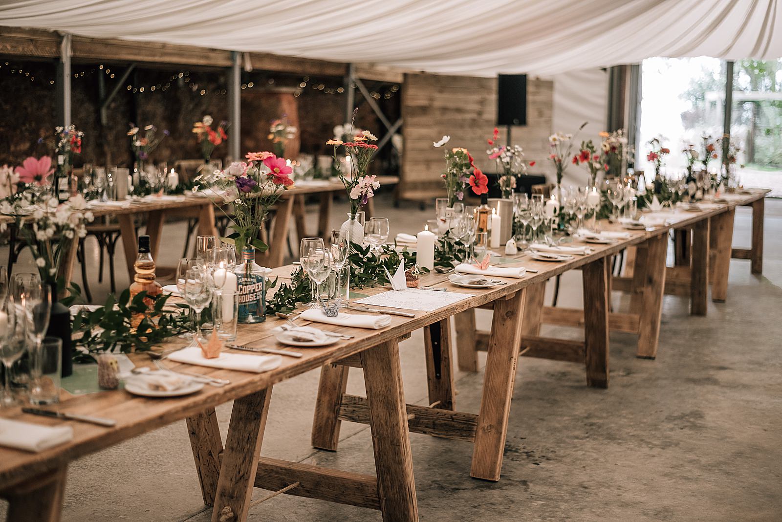 rustic wooden tables set with glassware, place settings and beautiful flowers for wedding at the cow shed scotland in barn