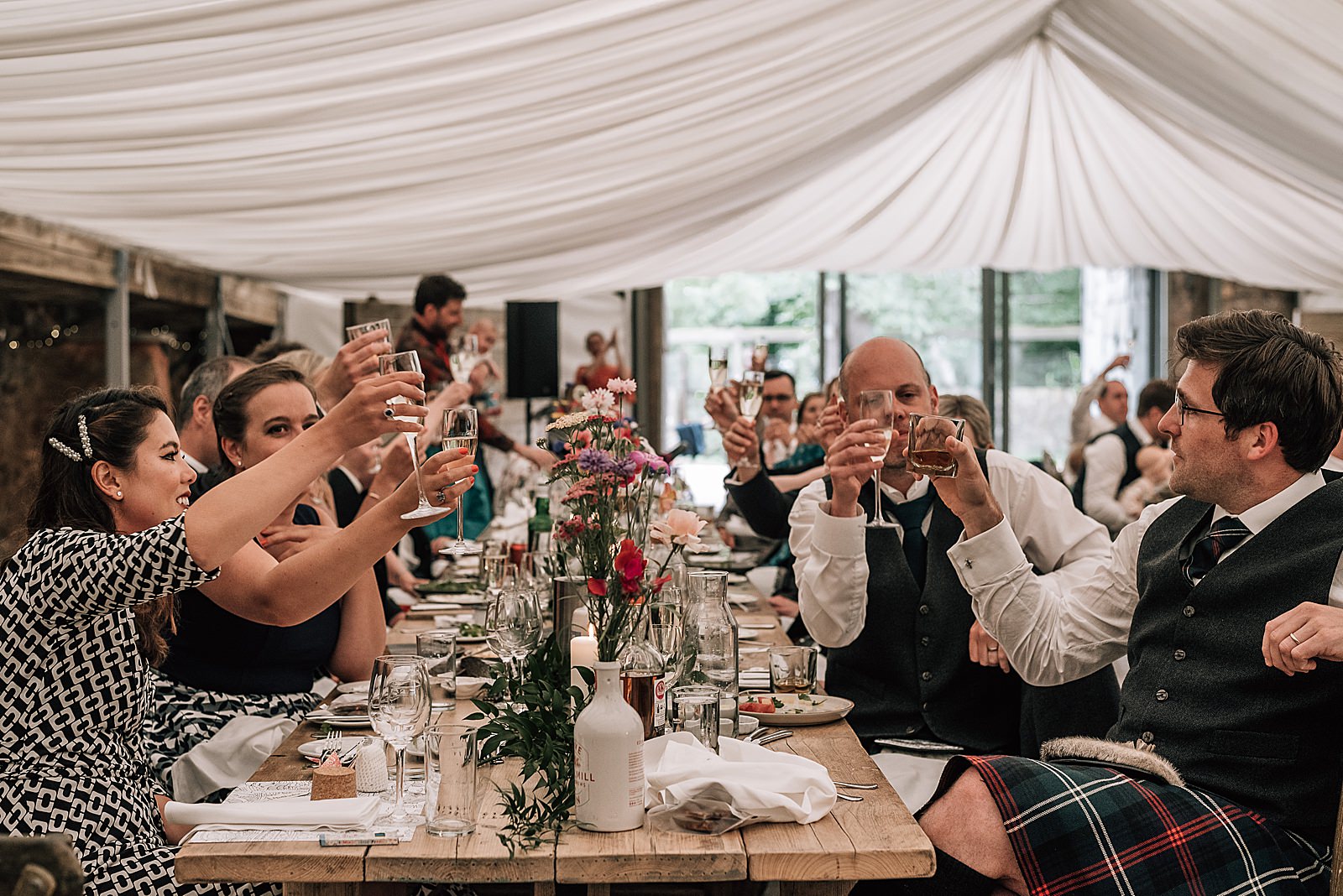 guests clinking glasses during wedding reception at the cow shed scotland