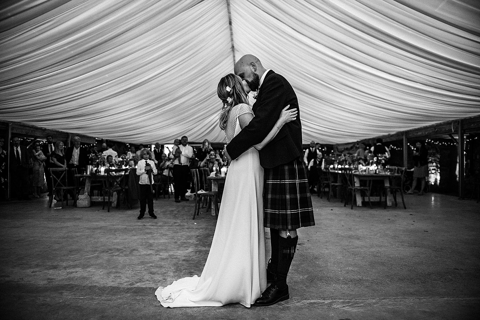 bride and groom kissing under tent roof at the cow shed scotland during their first dance