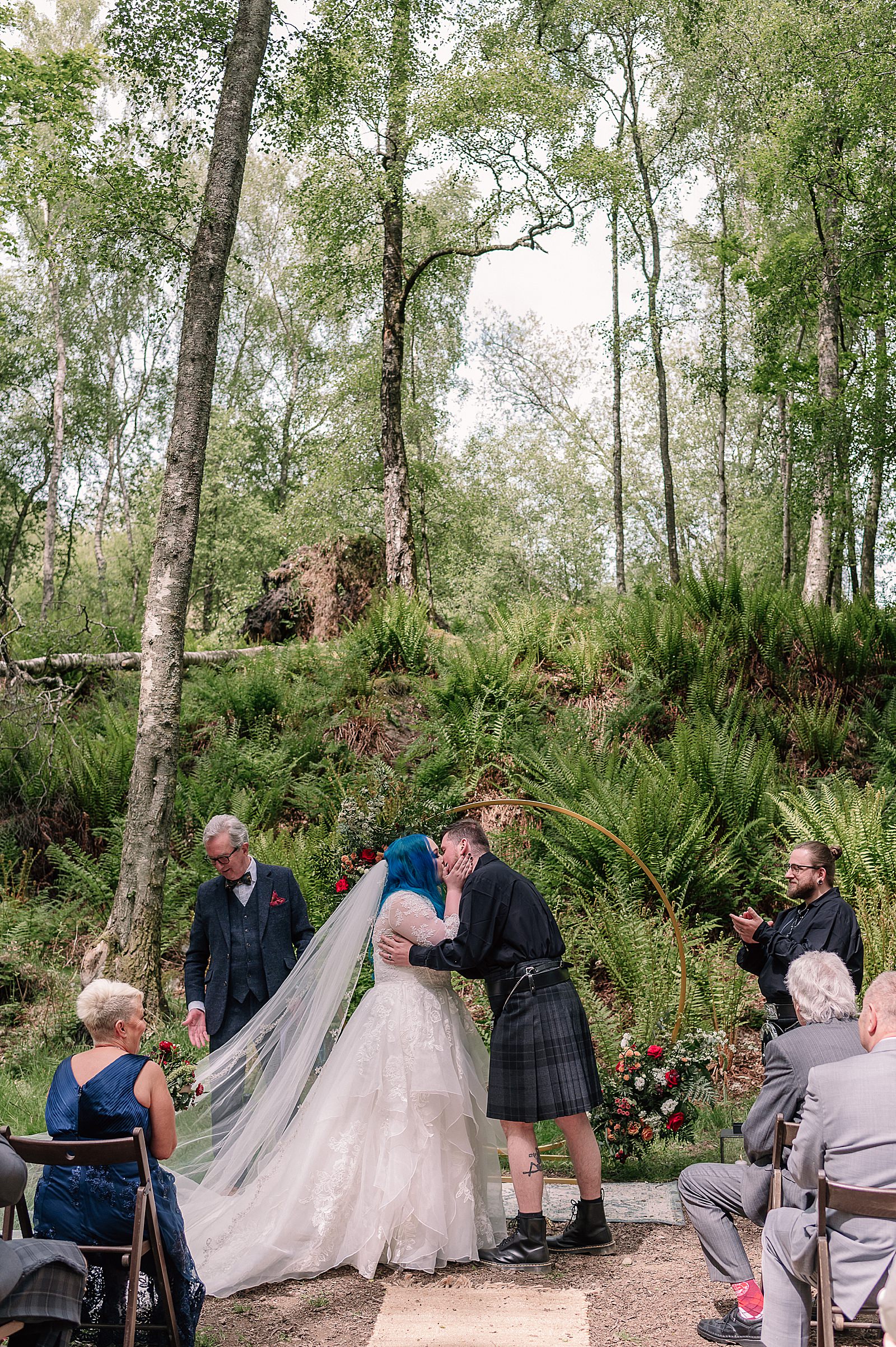 bride and groom kissing during their Scottish woodland wedding ceremony at comrie croft one of the best Scottish barn wedding venues in scotland