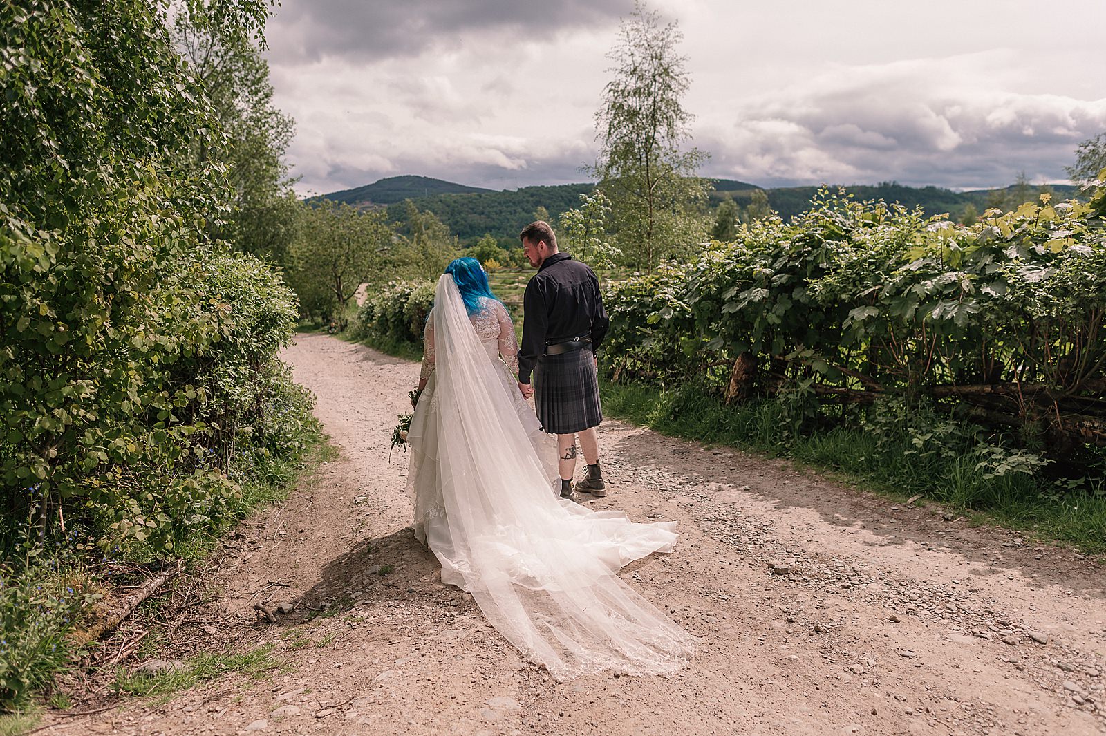 bride and groom walking down farm track for their Scottish barn wedding at comrie croft photographer by alternative wedding photographer scotland