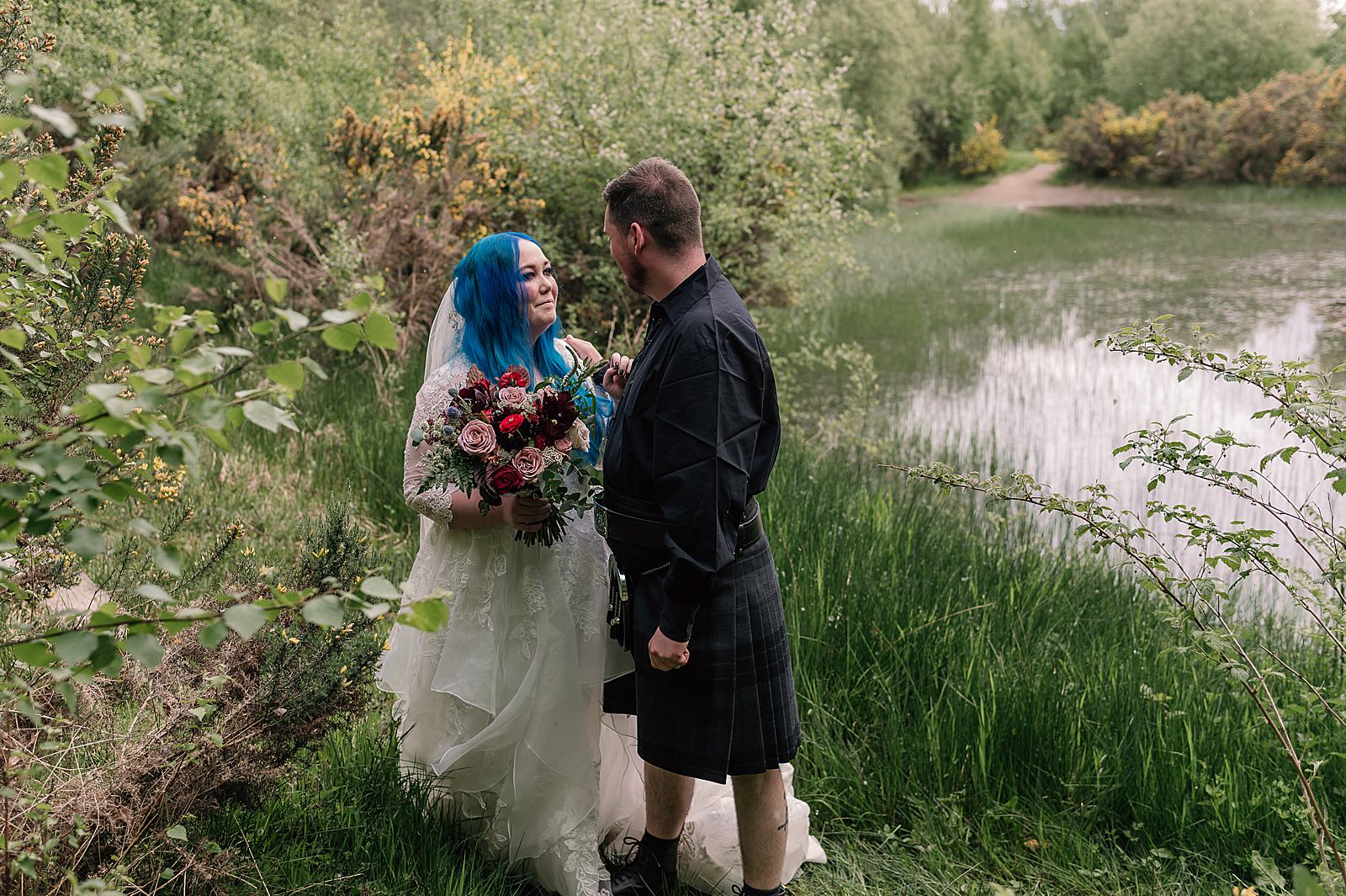 bride and groom looking at each other and smiling by the side of a small loch an after their comrie croft wedding ceremony photographed by an alternative wedding photographer scotland
