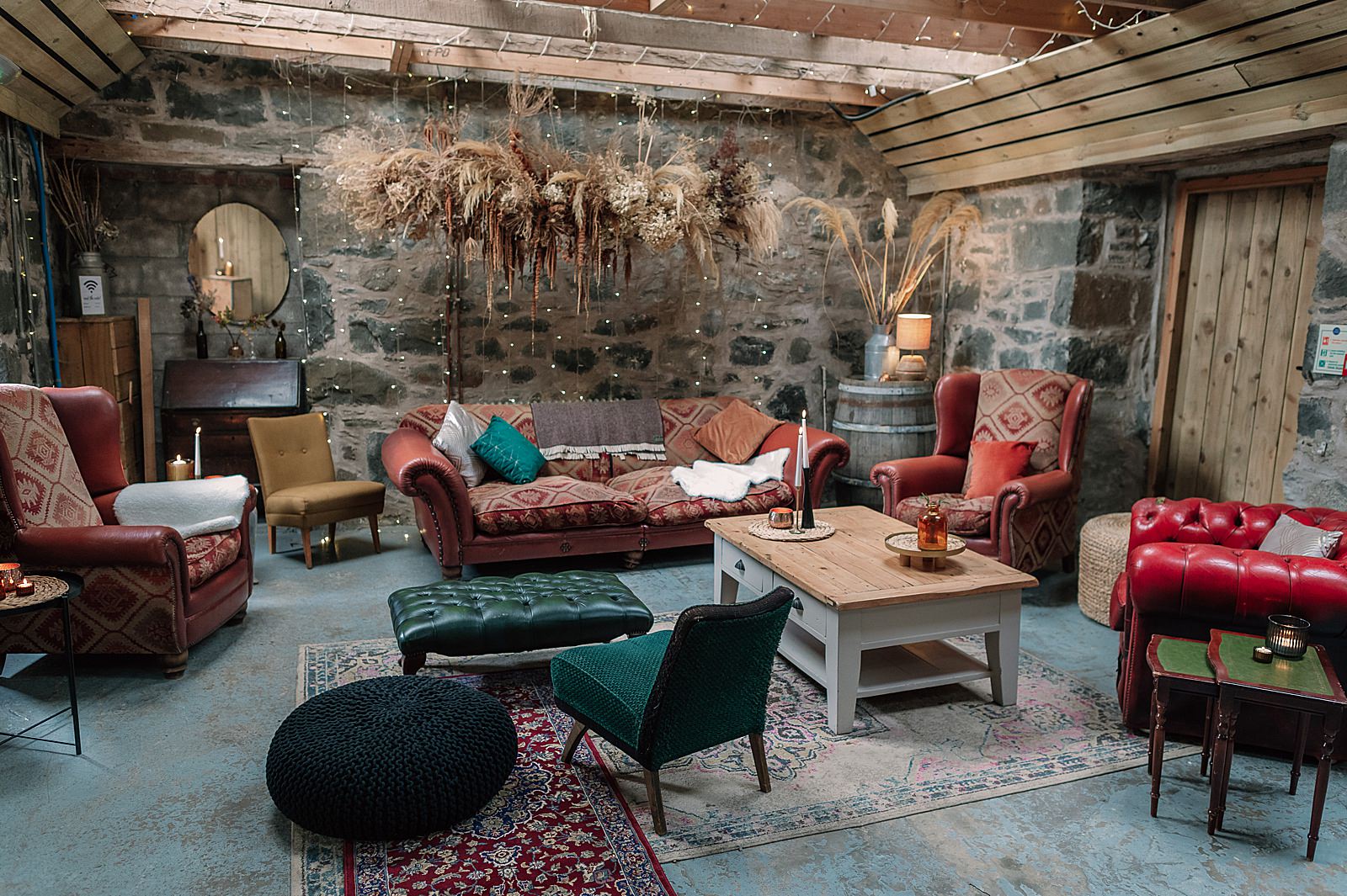 interior of Comrie Croft wedding venue with mix matched chairs inside barn with a hanging dried flower installation at one of the best Scottish barn wedding venues in scotland