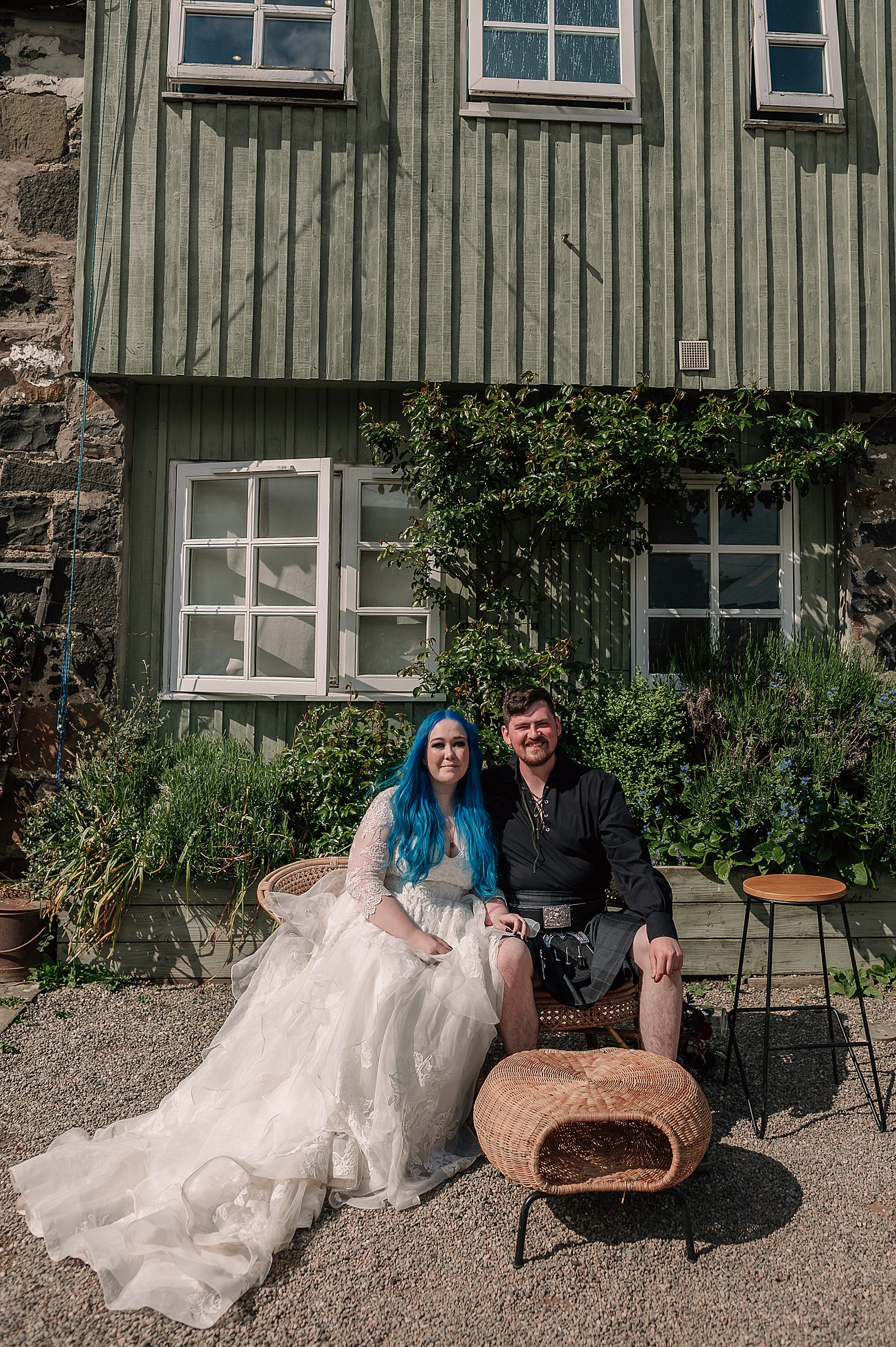 bride and groom sitting in courtyard smiling on a sunny day after their Comrie Croft wedding ceremony