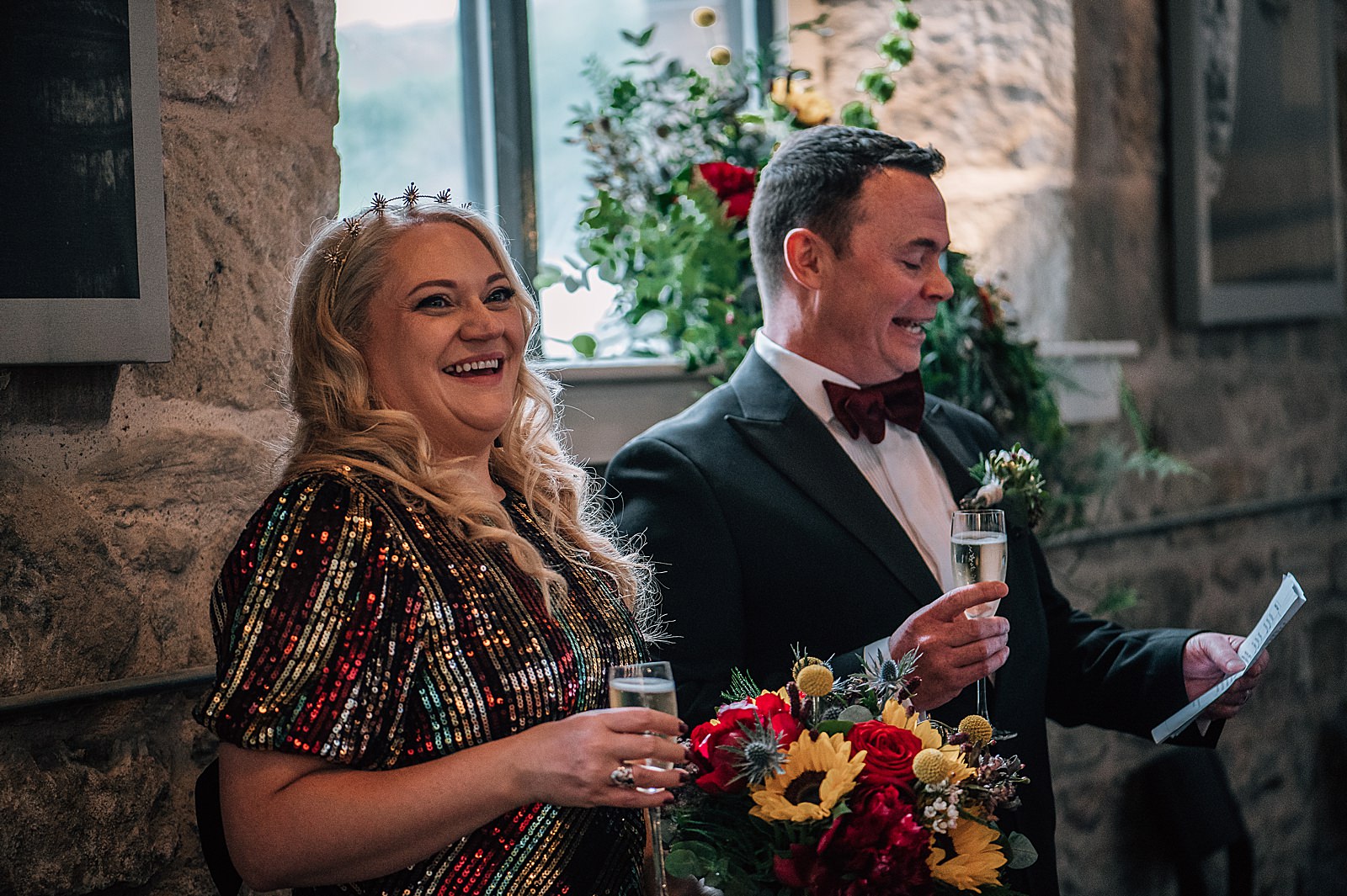 groom making a speech with his bride in sequin wedding dress and sunflower bouquet at clydeside distillery wedding scotland