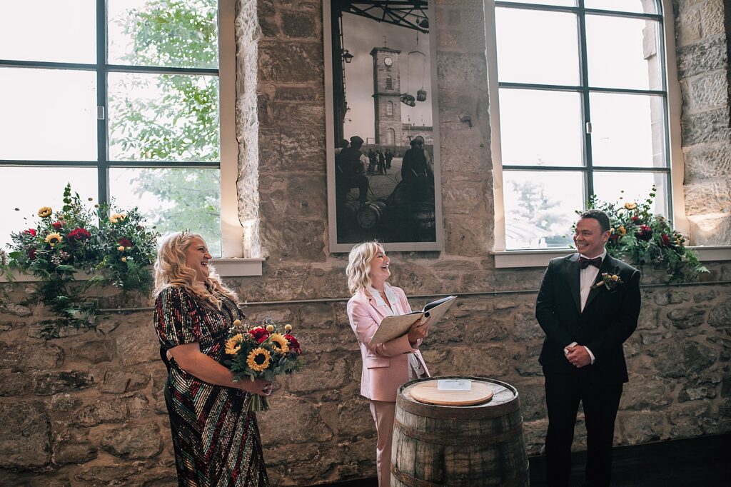 bride and groom laughing with celebrant at their distillery wedding scotland inside clydeside distillery