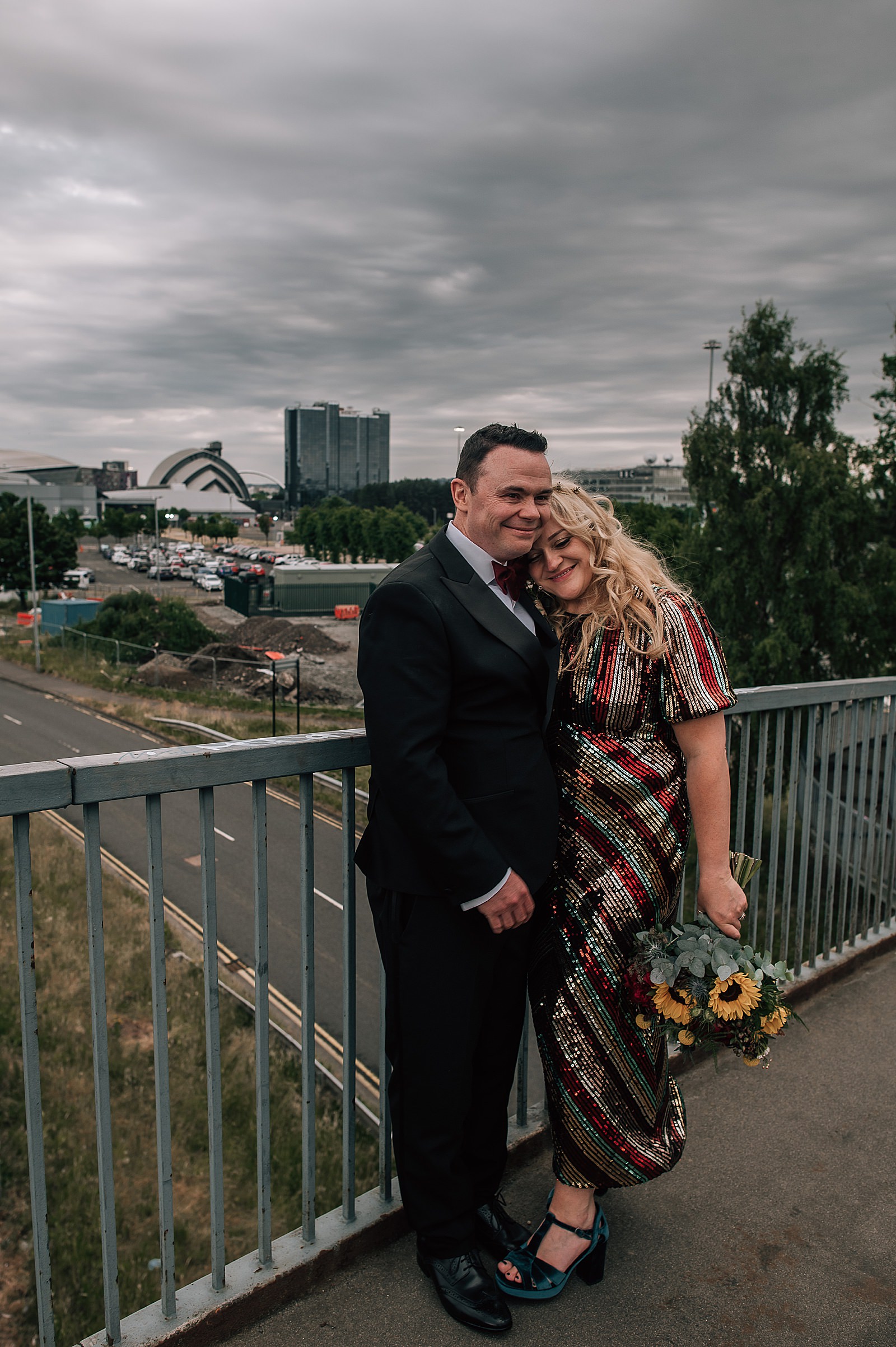 bride and groom hugging on bridge above clydeside expressway after ceremony at their distillery wedding scotland at clydeside distillery