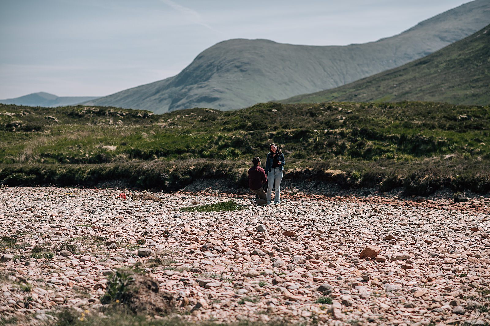 couple during surprise proposal in glencoe on a summers day in front of Lagangarbh hut captured by glencoe proposal photographer