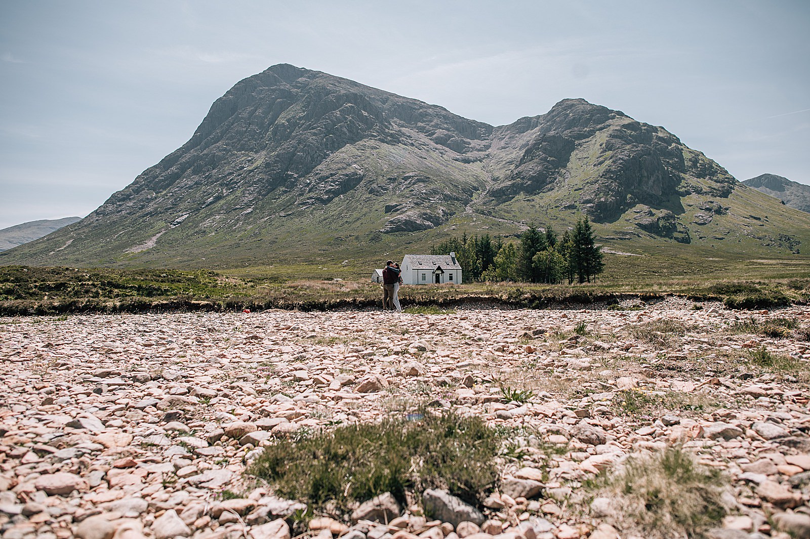 couple getting engaged in glencoe on a sunny day in front of Lagangarbh hut captured by glencoe proposal photographer