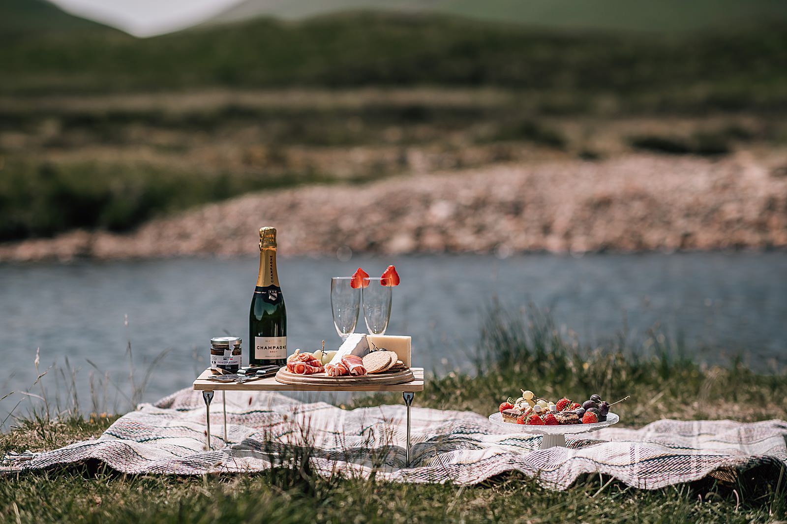 luxury Scottish picnic in glencoe with champagne, cheese and strawberries captured by glencoe proposal photographer