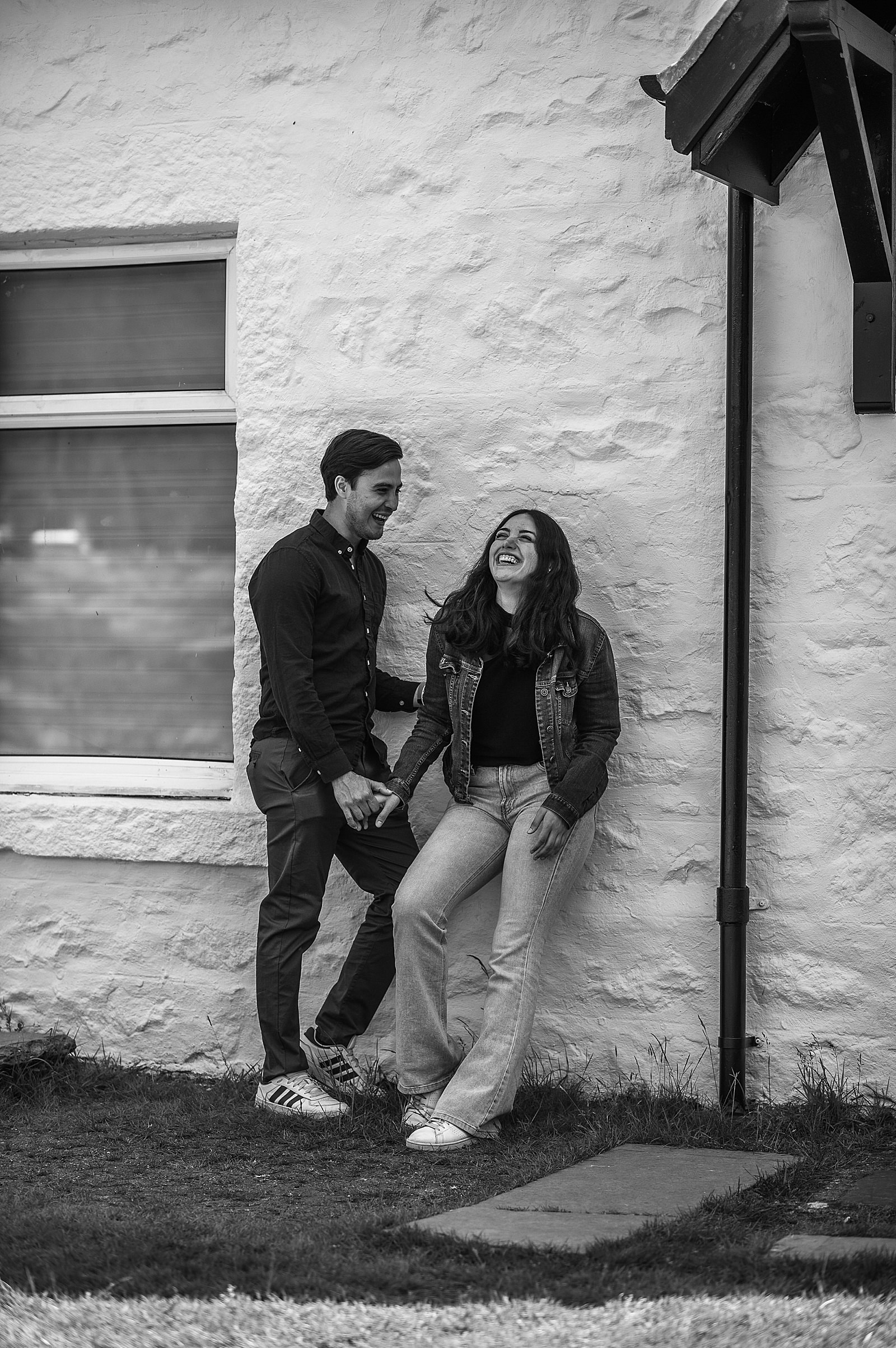 couple holding hands and smiling as they stand outside Lagangarbh bothy glencoe captured by glencoe proposal photographer