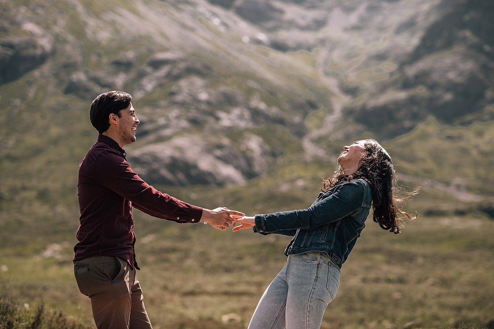 couple holding hands and dancing in front of buachaille etive mor during engagement photography scotland shoot