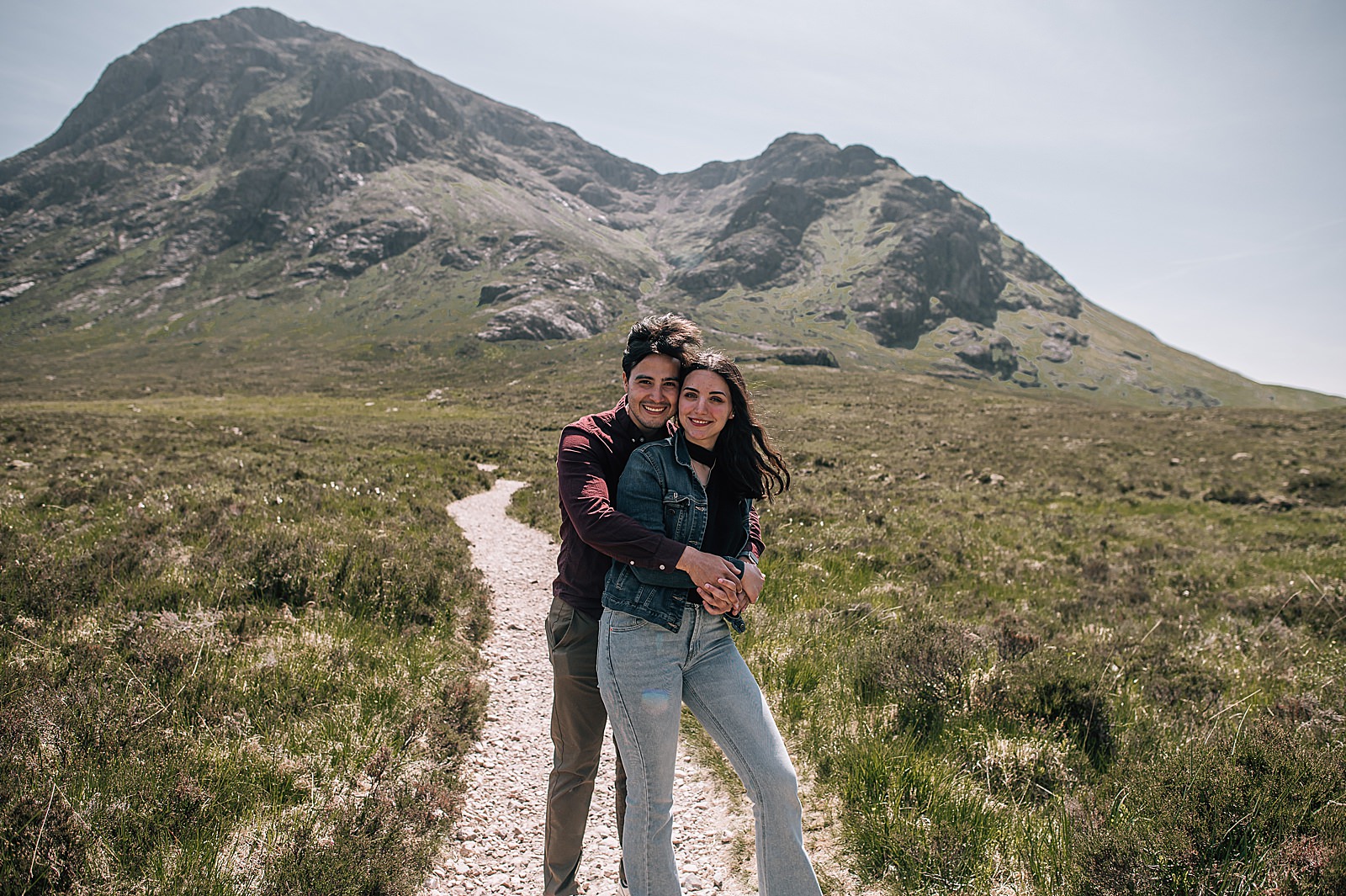 couple hugging in front of buachaille etive mor during their surprise engagement shoot captured by glencoe proposal photographer
