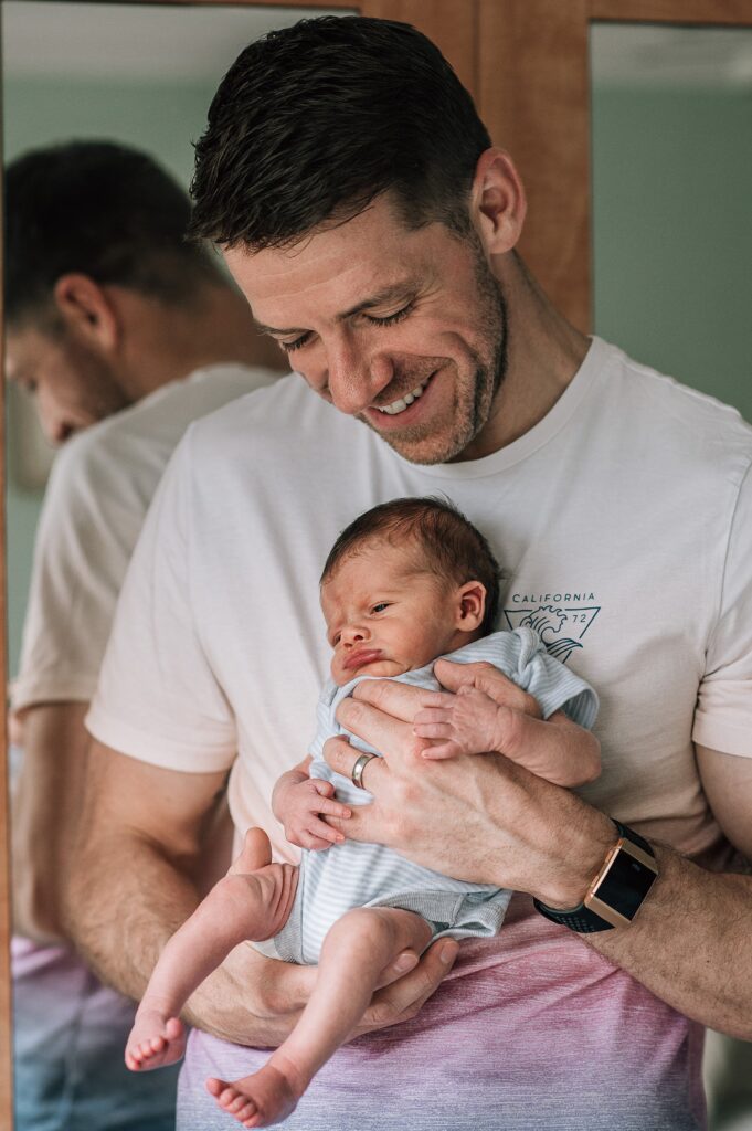 father smiling holding sleepy baby