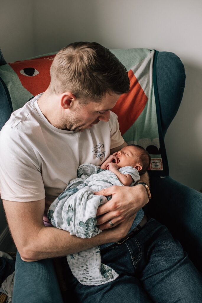 father cuddling baby on a chair