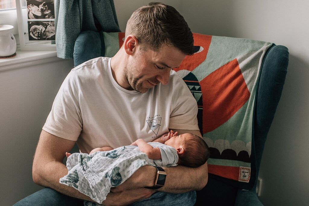 father sitting on chair cuddling baby