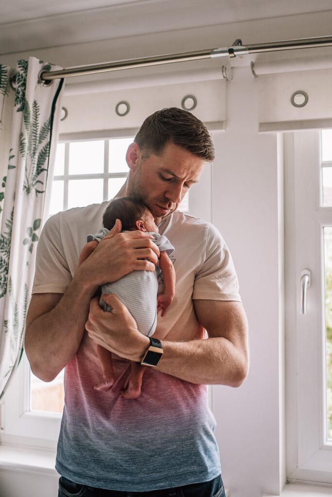 father cradling newborn baby