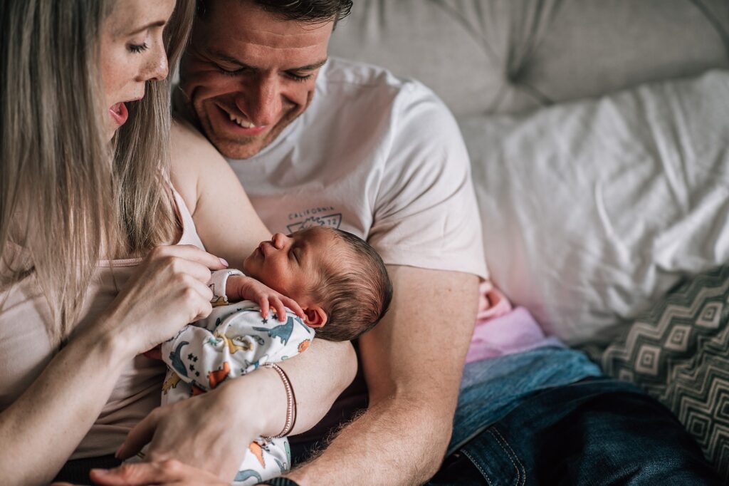 new parents cradling newborn baby on bed