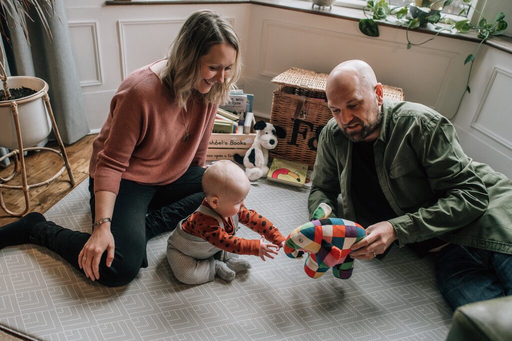 baby sitting on the floor with parents playing with patchwork elephant
