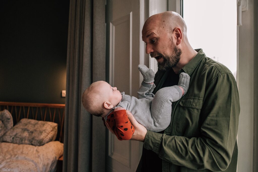 man playing with baby and pulling expressions