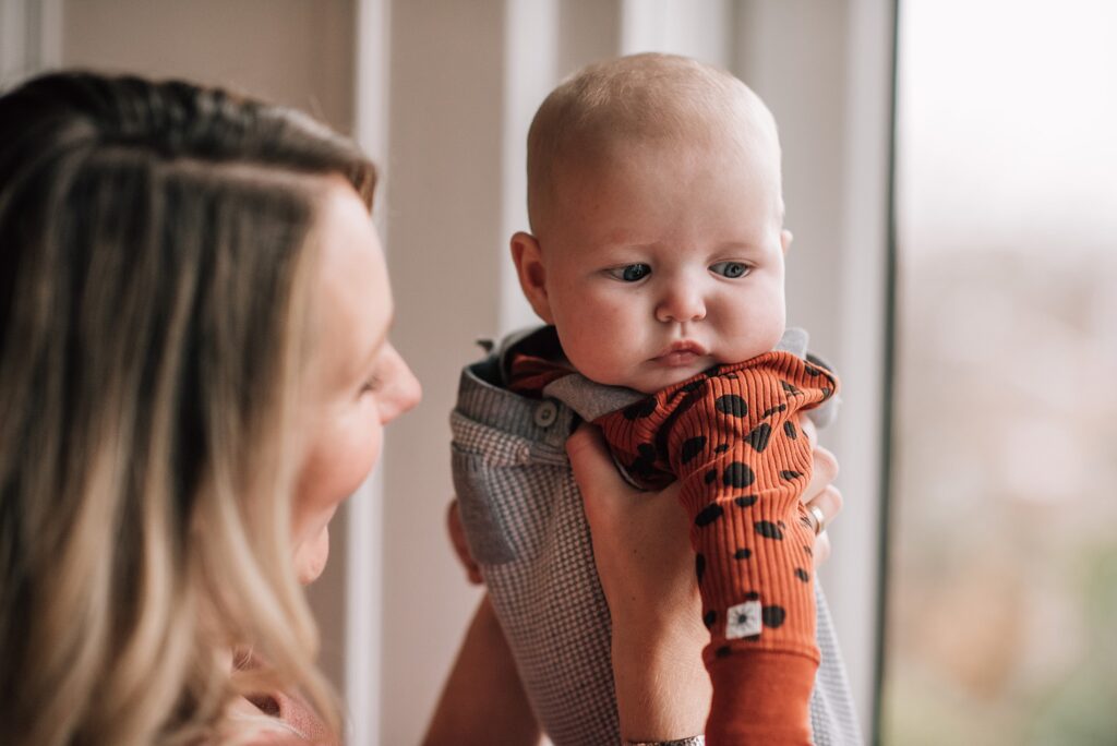 baby looking out window while being held by mother
