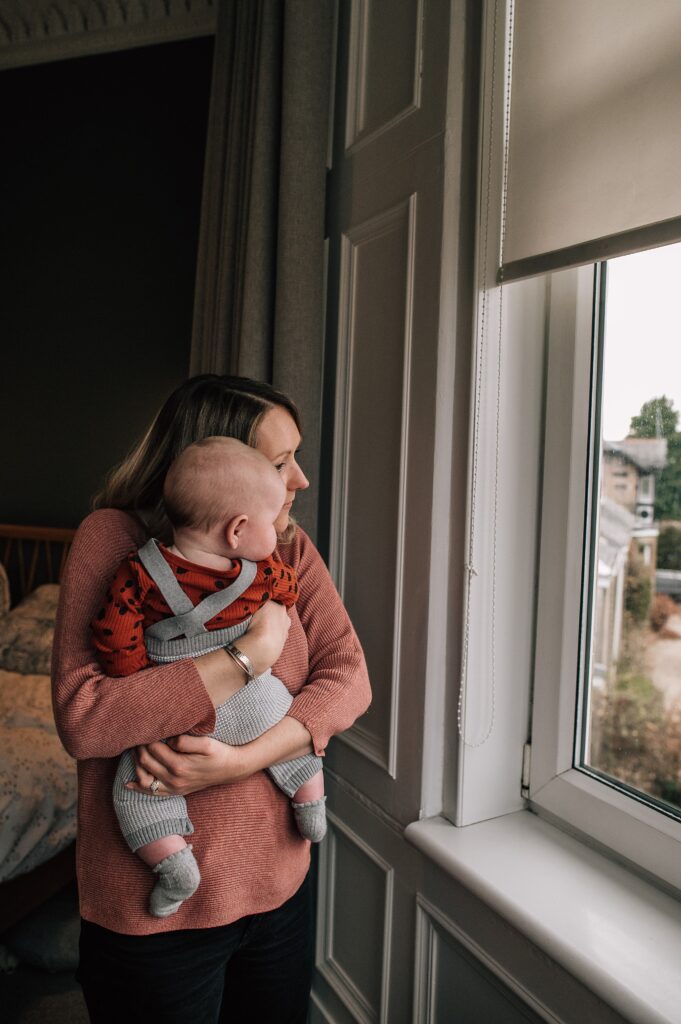 mum hugging her baby next to a window