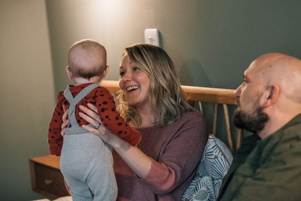 mum smiling at baby next to daddy