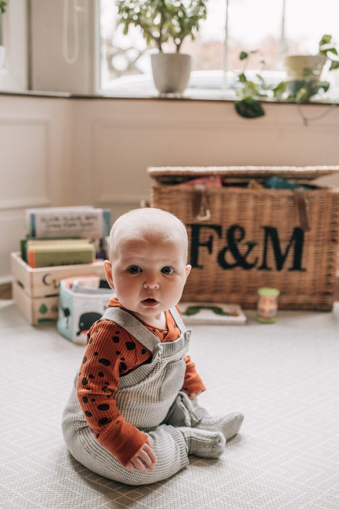 baby sitting upright on a grey rug