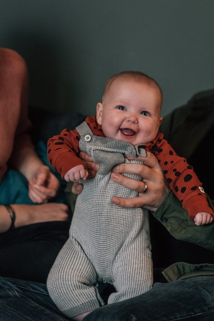 baby smiling while being held by parents