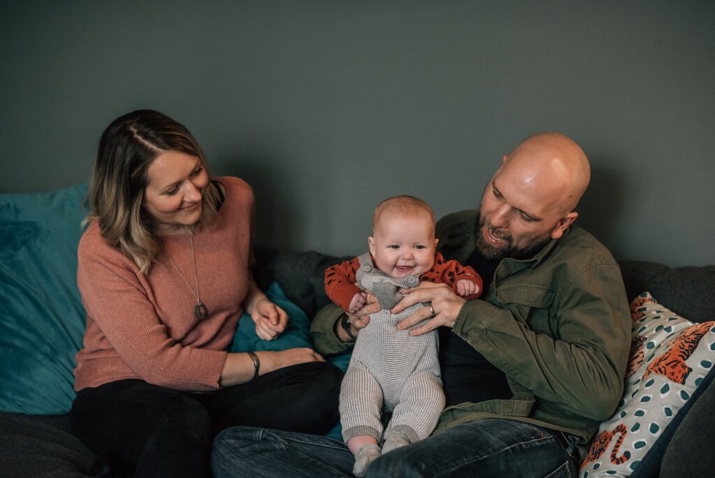parents sitting either side of baby and holding her and smiling