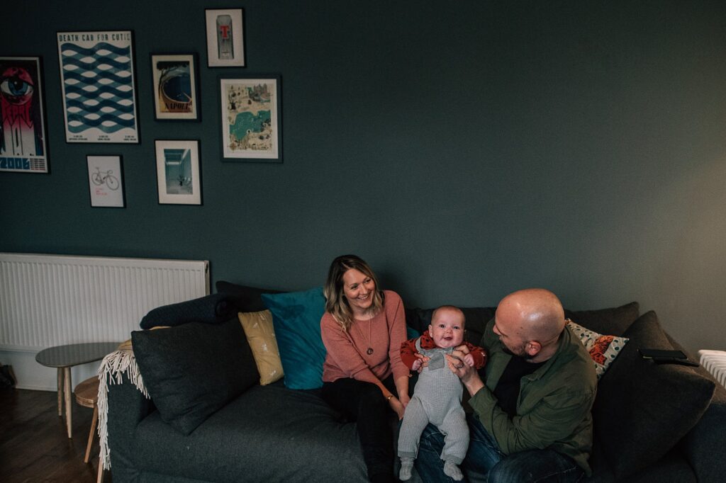parents holding baby while sitting on a sofa in a living room