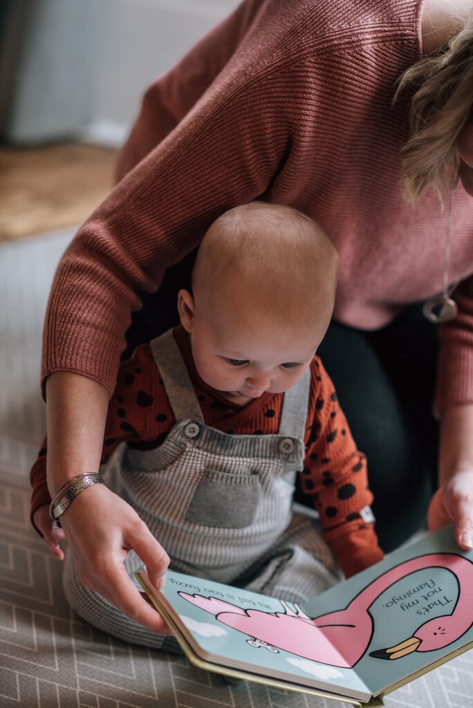 mum sitting behind baby reading a book with her 